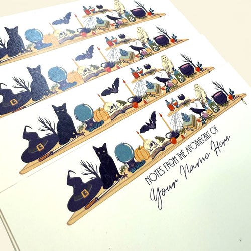 Personalized flat notecards with a witchy desk illustration featuring a black cat, globe, bat, potion bottles, and a witch.