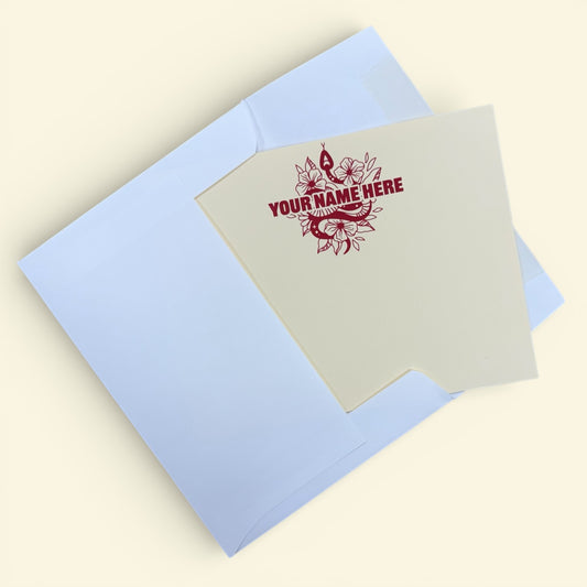 Cream notecard with red snake and floral design and customizable name text, paired with pale blue envelope.
