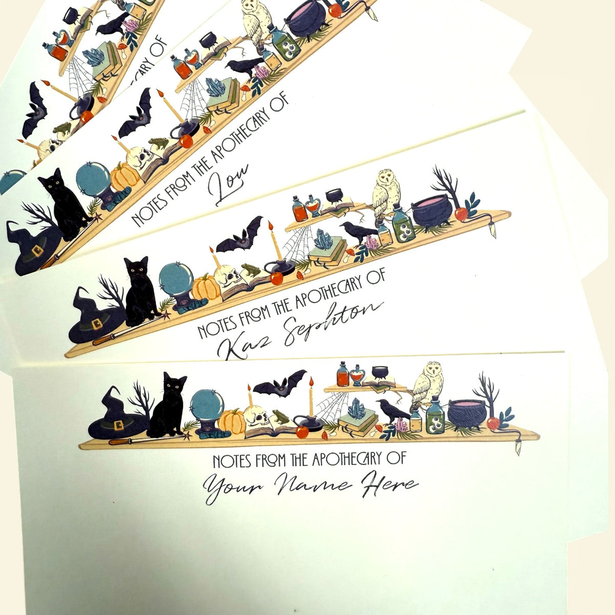 Set of personalized flat notecards with witchy desk illustration, featuring black cats, candles, skulls, and potions on a.