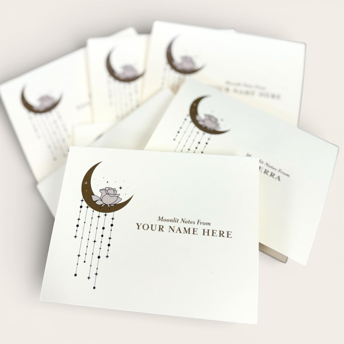 Set of folded white cards with a crescent moon and star design, customizable name text on front.