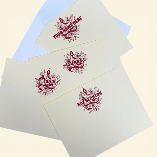 Set of personalized notecards with red snake and floral design featuring custom names on cream paper.