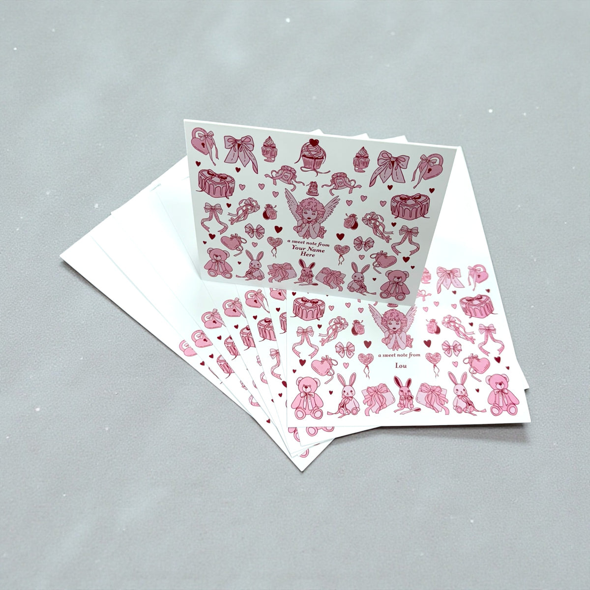 Set of 10 note cards with pink angel and heart collage design on white background, includes envelopes.