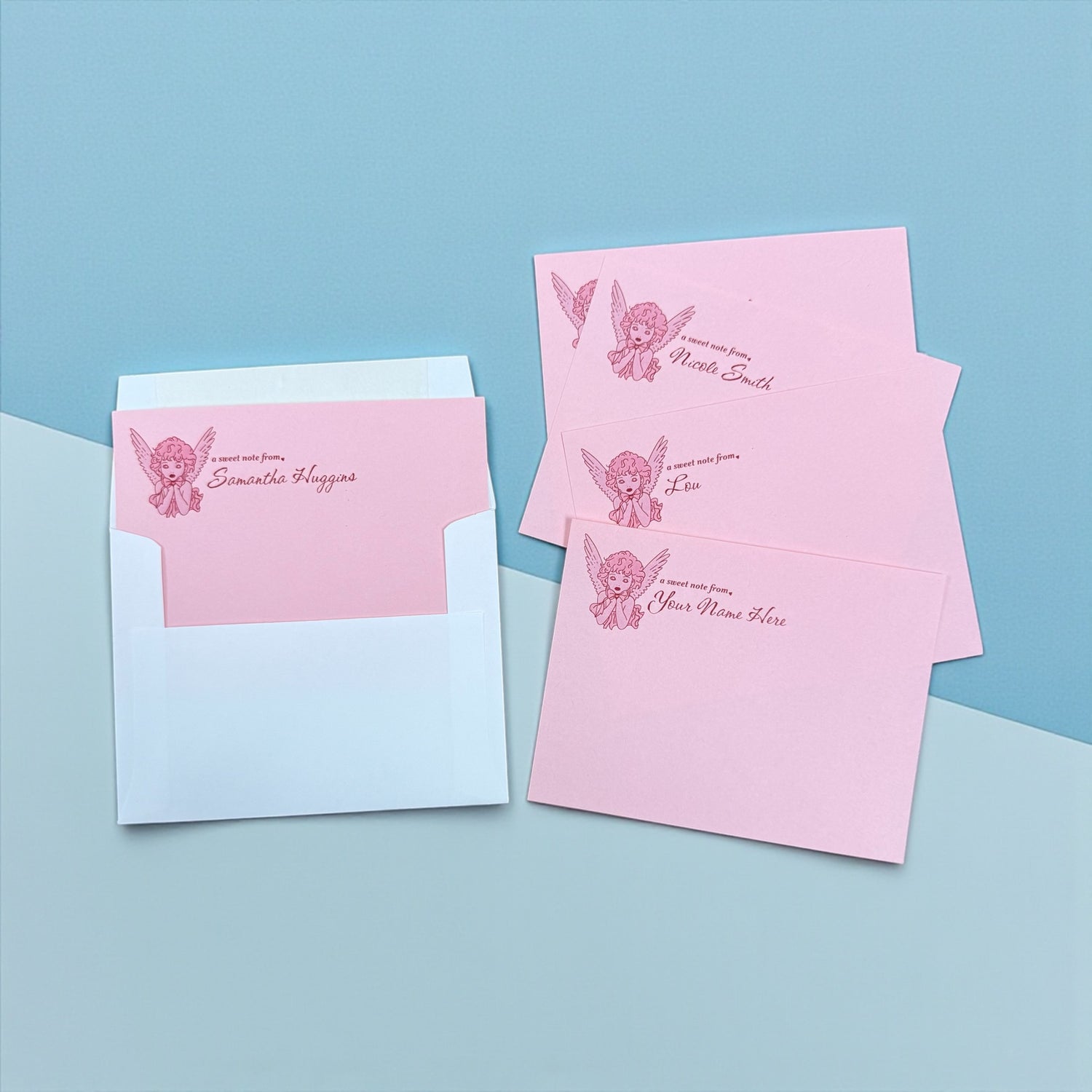 Set of pink personalized notecards with angel graphic and cursive text, paired with white envelopes.