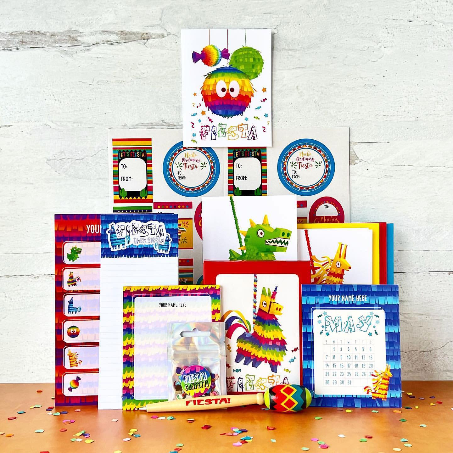 Collection of colorful Fiesta-themed party supplies on a wooden surface with a white brick wall background.
