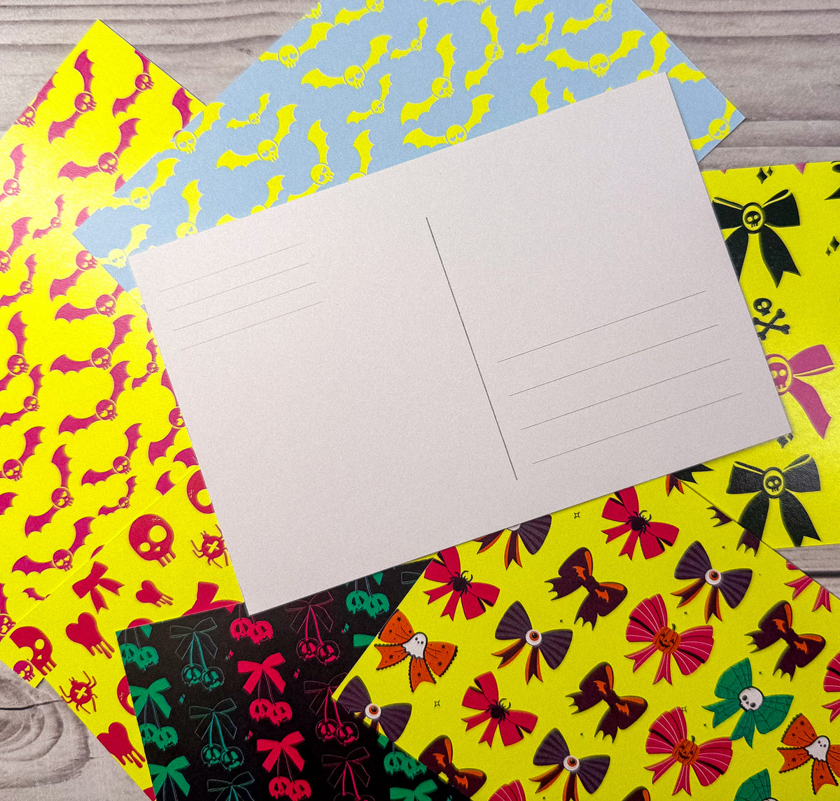Blank postcard on top of neon stationery featuring custom personalized designs of pink bats on yellow, yellow bats on blue,. - Neon Matching Notecards