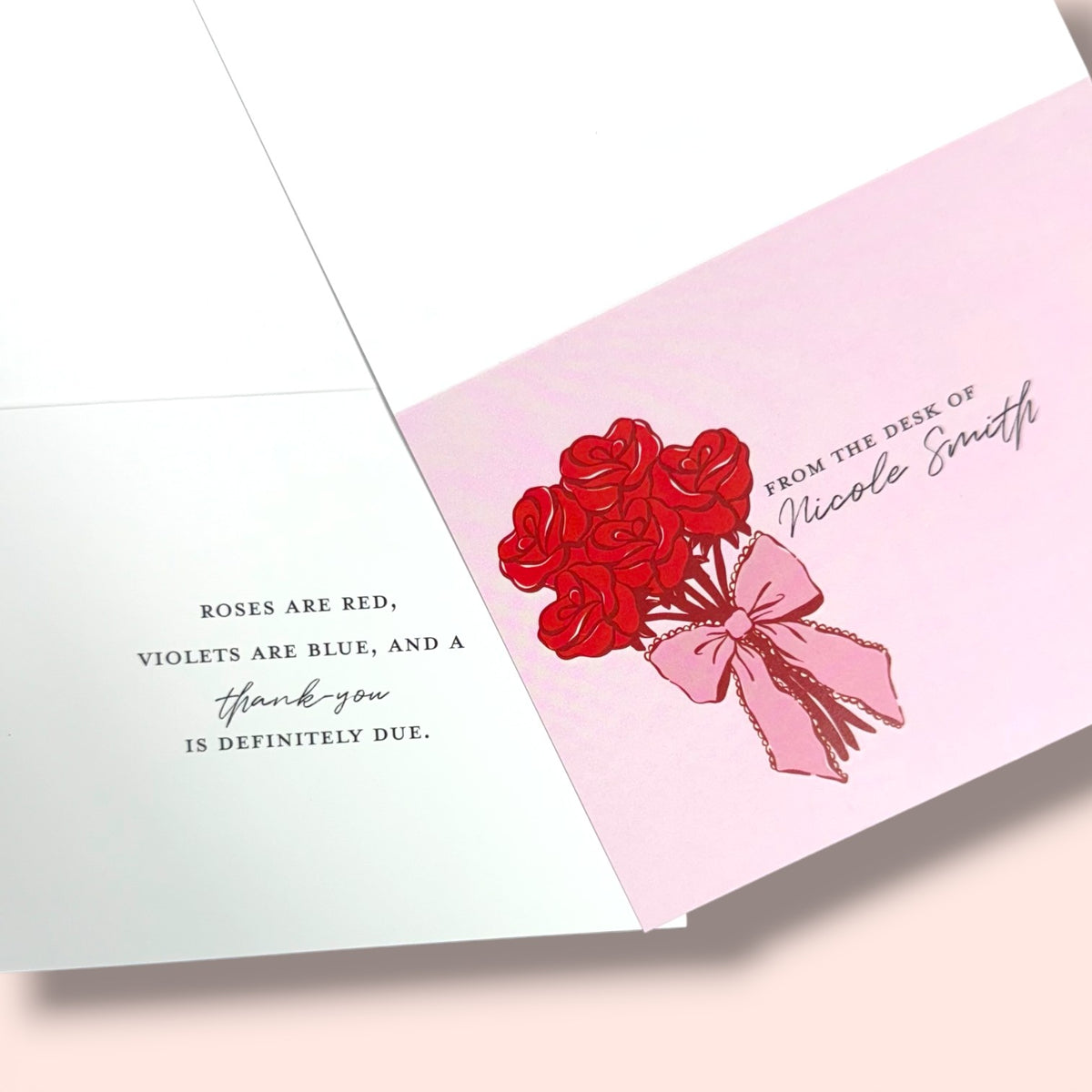 Open greeting card with pink cover featuring a red rose bouquet tied with pink ribbon and personalized script text inside.