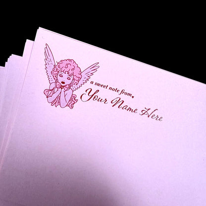 Pink stationery with angel illustration and customizable text on a black background
